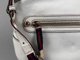 a close up of a white purse with a red, blue and white stripe strap