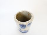un petit vase bleu et blanc posé sur une surface blanche