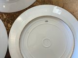 three white plates with gold rims are sitting on a table