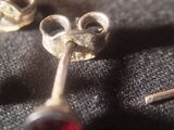 a pair of earrings that are sitting on a black cloth