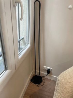 un lampadaire noir près d'une fenêtre dans une chambre à coucher