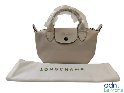 a longchamp bag sitting on the table next to a white bag