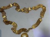 a close up of a gold necklace with a pearl on it