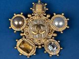 an image of a gold broochle with pearls and stones