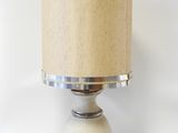 lampe de table beige et argentée avec un abat-jour beige sur fond blanc
