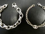 two silver bracelets on a black surface with a silver chain