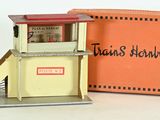une petite maquette d'un poste de secours, devant une boîte orange