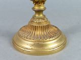 a gold clock on a gold pedestal on a table
