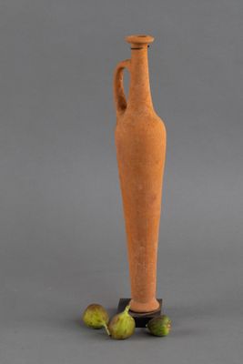 un petit vase muni d'une anse, posé sur un socle à côté de quelques figurines