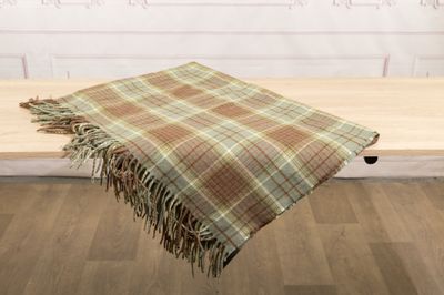 a plaid blanket on a wooden table in front of a white wall