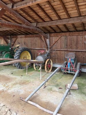 un tracteur garé dans une grange, à côté d'une clôture en bois