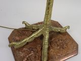 a gold colored lamp with a bird ' s feet on it
