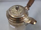a silver tea pot with a wooden handle on a table