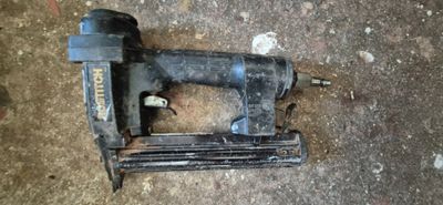 une photo montrant une agrafeuse et un pistolet à clous posés par terre