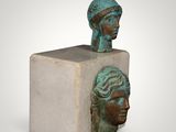 a close up of a sculpture of two heads on a block
