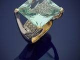 a gold ring with an emerald stone on a blue background
