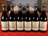 six bottles of wine are lined up in a row on a table