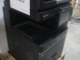 une pile d'imprimantes posée sur une palette dans un entrepôt