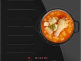 une plaque de cuisson électrique noire sur laquelle est posé un bol de soupe