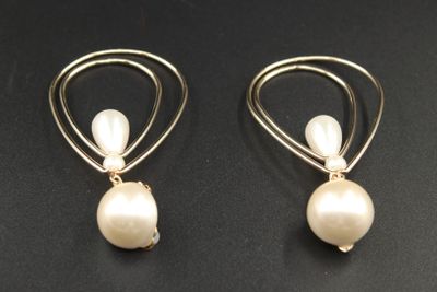 une paire de boucles d'oreilles en perles et en or posées sur un fond noir