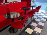 des tables et des chaises dans un restaurant aux murs rouges et au sol à carreaux