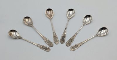 six silver spoons are arranged in a circle on a white surface