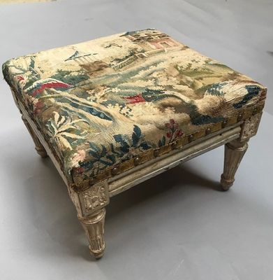 un tabouret ancien dont l'assise est recouverte d'un tissu à motifs floraux