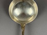 silver spoon on a gray surface with a silver ball in the center