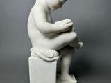 marble statue of a boy sitting on a box reading a book