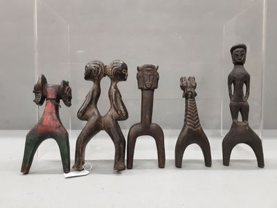 quatre figurines en bois de formes et de tailles différentes, présentées dans une vitrine