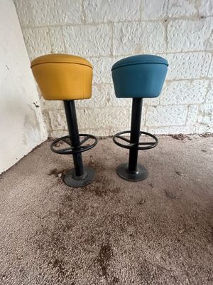 une paire de tabourets jaunes et bleus posés devant un mur de briques blanches