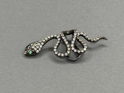 un gros plan d'une broche en forme de serpent posée sur une surface grise