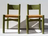 two green chairs sitting next to each other against a white wall