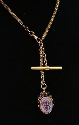 un collier composé d'une chaîne en or et d'un pendentif en verre rose