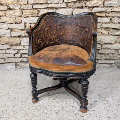 une vieille chaise avec une assise en cuir marron, posée devant un mur de pierre