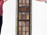 two people standing next to a tall stained glass window