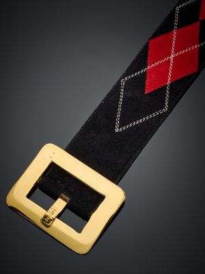 un gros plan sur une ceinture noire et rouge dotée d'une boucle dorée