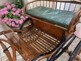 a wooden bench with a green seat next to a flower pot