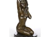 une statue en bronze représentant une femme assise sur un socle en marbre