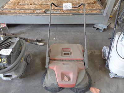 a lawn mower sitting on the floor next to other items