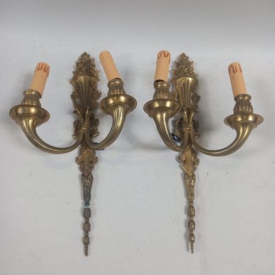 pair of antique brass wall sconces with candles on each of them