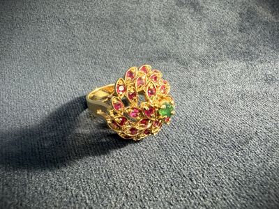 a close up of a gold ring with pink and green stones