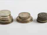 trois piles de pièces empilées les unes sur les autres sur une surface blanche