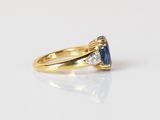 a yellow gold ring with a blue sapphire and two diamonds