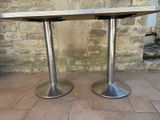 pair of stainless steel pedestals on a brick patio with a stone wall in the background