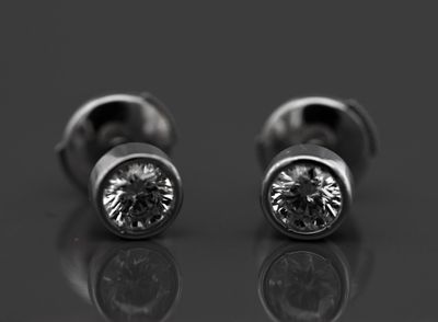 une paire de boucles d'oreilles en diamant posée sur une surface réfléchissante