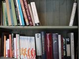 a bookshelf with many books on it and a clock on the wall