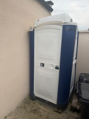 des toilettes portables blanches et bleues à côté d'une poubelle