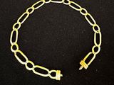un bracelet en chaîne dorée muni d'un fermoir, sur fond noir
