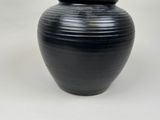 a black vase that is sitting on a white surface
